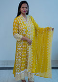 Woman wearing a yellow and white patterned outfit with a matching dupatta against a plain background